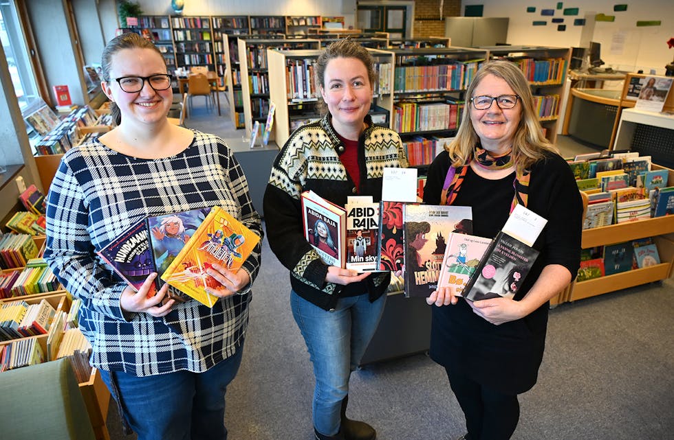 UTLÅNSTOPPAR: Katrine Thorstensen, Ingvild Elvestad Tørre og Sigrid Bjerke med bøker som var blant dei meste utlånte ved Midt-Telemark bibliotek i 2022.